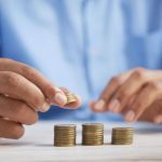 Investment Commodities - a person stacking coins on top of a table